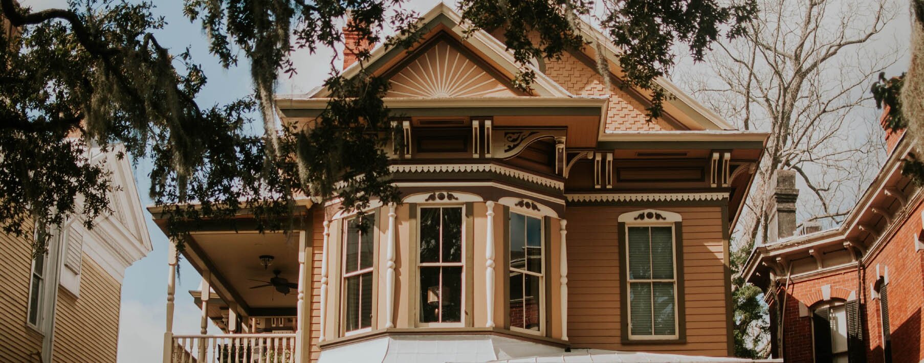 Photo of an older home with a bay window and a patio on the side
