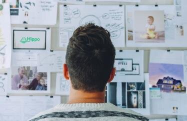 homeowner looking at bulletin board with various papers on it