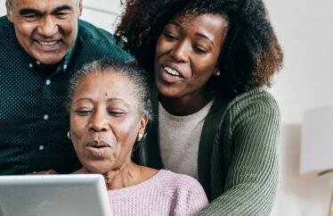 A young woman showing an older couple a tablet.