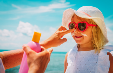 child getting sunscreen applied on their face by an adult