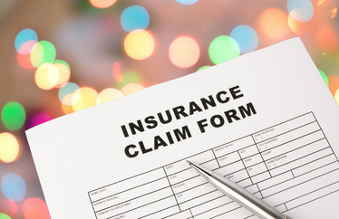 insurance home claims paper form in front of a background of blurred holiday lights
