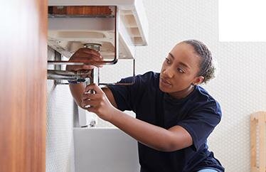 homeowner fixing pipes under the bathroom sink